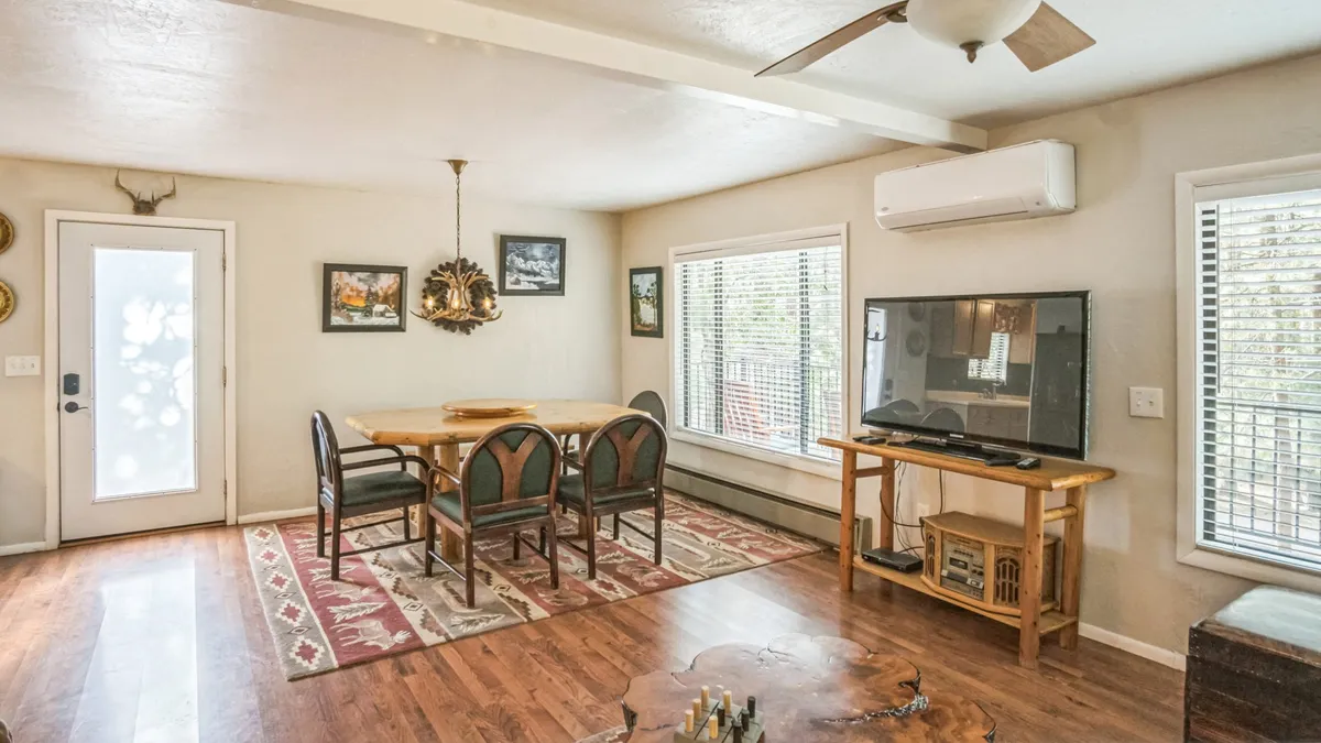 A warm dining area featuring a central table illuminated by a chandelier, with expansive windows for natural light. The space is ideal for family meals, playing games, and sharing stories after a day outdoors or visiting local attractions.