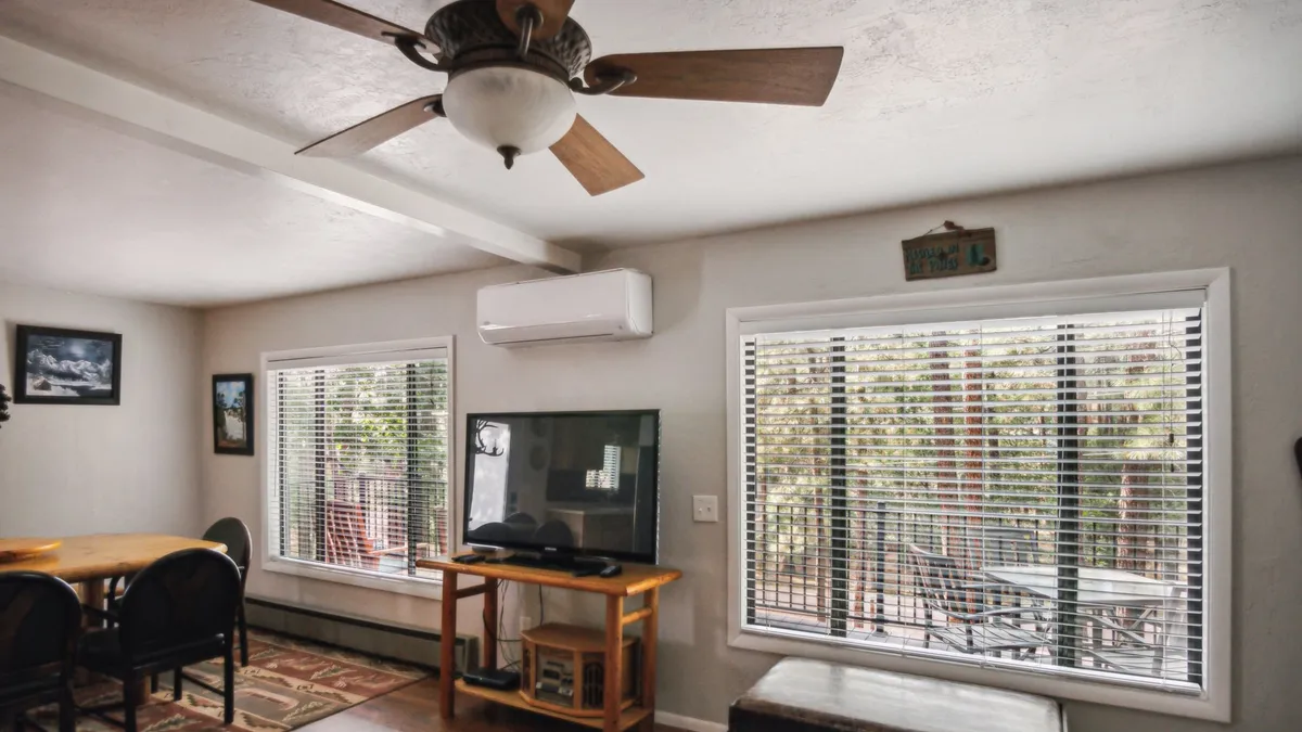 A cozy interior dining space featuring a wooden table set near large picture windows, with a television mounted on the wall. The setup invites families to gather for meals, share stories, and enjoy views of the outdoors, hinting at the connection between indoor comfort and outdoor experiences.