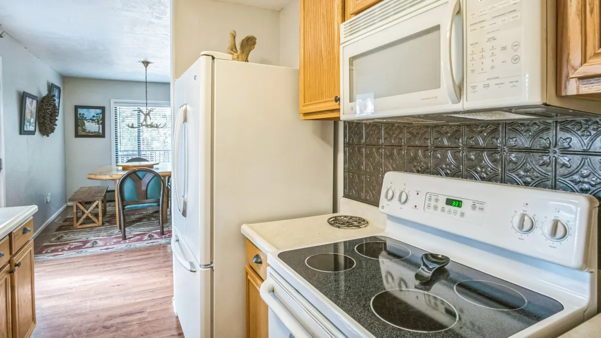 This image shows an inviting kitchen and dining area, complete with modern appliances, a cozy dining table, and decorative touches that evoke a sense of warmth and hospitality. The space is well-lit and arranged for social activities, suggesting a welcoming environment for gathering with friends or family.